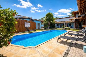 a swimming pool with lounge chairs next to a house at Pousada Universo Arraial in Arraial d'Ajuda