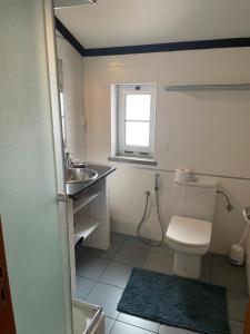 a bathroom with a toilet and a sink and a window at Refúgio Das Ondas in Praia da Vitória +5 photos