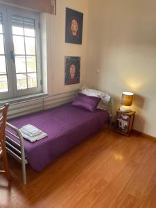 a bedroom with a purple bed and a window at Refúgio Das Ondas in Praia da Vitória