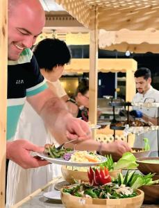a chef preparing food at a buffet in a restaurant at Wadi Rum Elara Luxury Camp in Wadi Rum