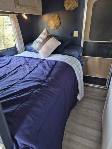 a bedroom with a large blue bed in a room at Knot Work Cayuga Lake 30ft Boat in Ithaca +4 photos