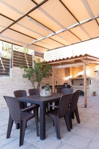a black table and chairs under a patio umbrella at La Casa Seni Near Athens Airport in Papangeláki