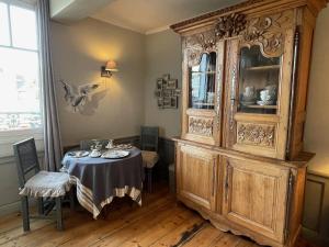a dining room with a table and a large wooden cabinet at La Poupardoise in Honfleur