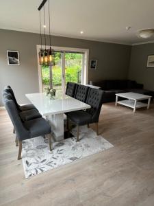a dining room with a white table and black chairs at Krøgeneslåven Microtel in Arendal