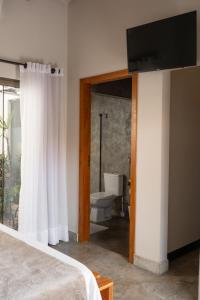 a bedroom with a bed and a bathroom with a toilet at Sattva Pousada in Pirenópolis +43 photos