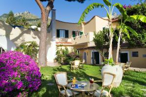 einen Hinterhof mit einem Tisch, Stühlen und Blumen in der Unterkunft Villa Angela Hotel & Spa in Ischia