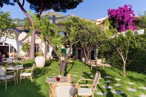 einen Garten mit Tischen, Stühlen und Bäumen in der Unterkunft Villa Angela Hotel & Spa in Ischia