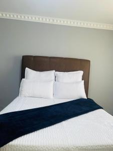 a bed with white pillows and a brown headboard at R&N Hosts in Maseru