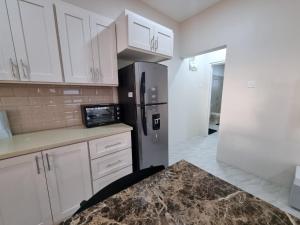a kitchen with white cabinets and a stainless steel refrigerator at Sunset Apartment in Grand Anse