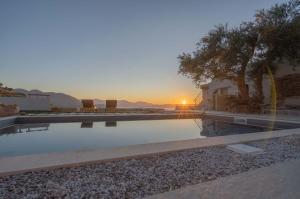 a swimming pool with a sunset in the background at Villa Maestoso in Mirsíni
