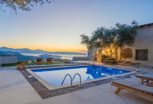 a swimming pool with a sunset in the background at Villa Maestoso in Mirsíni +42 photos