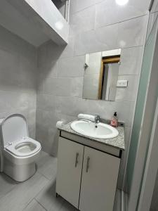 a white bathroom with a toilet and a sink at Amazing Home - Habitación Triple in Baños