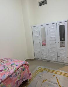 a bedroom with a bed and cabinets and a rug at Ajman Beach Apartments in Ajman 