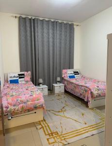 a bedroom with two beds and a curtain at Ajman Beach Apartments in Ajman 