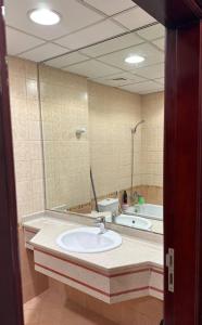 a bathroom with a sink and a large mirror at Ajman Beach Apartments in Ajman 