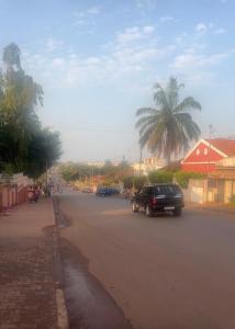 a car driving down a street with a palm tree at Casa Tolentino in Bissau