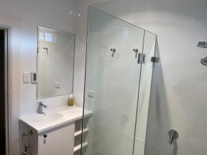 a white bathroom with a sink and a shower at Armidale Central Guest House in Armidale