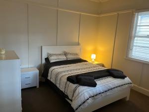 a bedroom with a bed and a lamp and a window at Armidale Central Guest House in Armidale