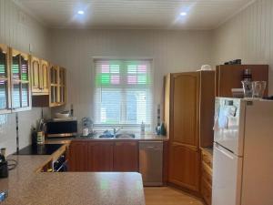 a kitchen with wooden cabinets and a white refrigerator at Armidale Central Guest House in Armidale