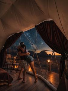 a couple kissing in a tent with a view of the stars at Lela camp in Al Mudawwarah