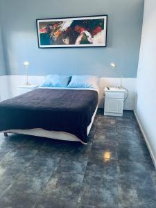 a bedroom with a bed and a painting on the wall at Tu rincón, lugar de descanso in Chascomús