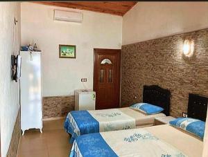 a hotel room with two beds and a refrigerator at H A Pansiyon in Ayvacık