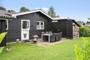 a black house with a table and chairs in a yard at FY147-Middelfart-Antaresvej-6 in Middelfart