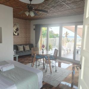 a bedroom with a bed and a table and a balcony at Bellas Guest House in Pooc