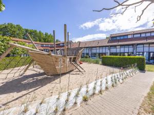 a wooden boat sitting in the sand in front of a building at Duinengolf - Zeeanemoon 10 in Westende