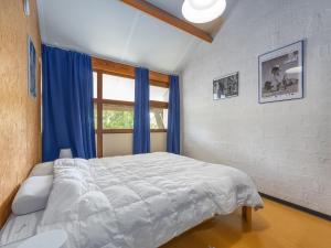 a bedroom with a bed with blue curtains and a window at Duinengolf - Zeeanemoon 10 in Westende