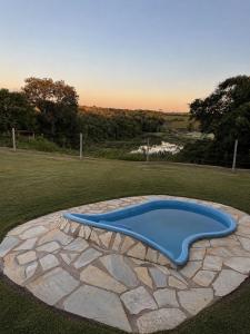 a blue swimming pool in a grassy field at Pousada Canastra Raíz in Delfinópolis