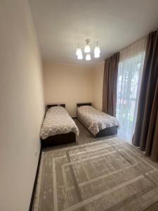 a bedroom with two beds and a window at РадугаВест58а in Koshkolʼ +15 photos
