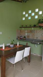 uma sala de jantar com uma mesa de madeira e cadeiras brancas em ReCanto dos Passáros - Guaratiba em Pedra de Guaratiba