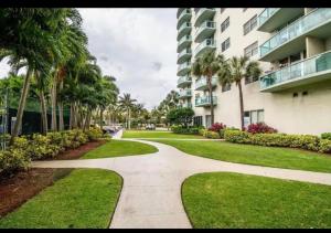 a walkway in front of a building with palm trees at Ocean Reserve Miami Sunny Isles Collins Ave in Sunny Isles Beach