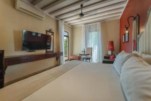 a bedroom with a large bed and a flat screen tv at Casa Zafiro Hotel - Adults Only, Mérida in Mérida