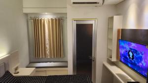 a room with a tv and a bed and a window at Transpark Juanda by Aqillaroom in Padurenan