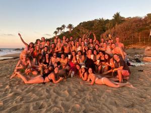 a large group of people posing for a picture on the beach at La Redonda Surf Hostel Sayulita in Sayulita