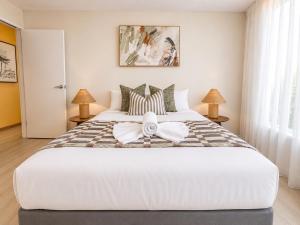 a bedroom with a large white bed with a bow on it at Alex Headland Unit Views to the Ocean in Alexandra Headland