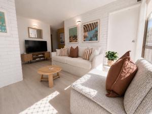 a living room with a couch and a television at Alex Headland Unit Views to the Ocean in Alexandra Headland