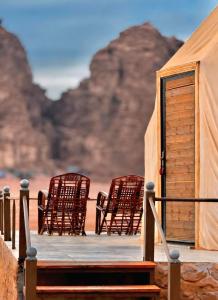 a group of chairs sitting on a wooden deck at Wadi Rum Elara Luxury Camp in Wadi Rum