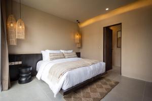 a bedroom with a large bed with white sheets and pillows at SISI Wellness Villas in Bingin Beach +46 photos