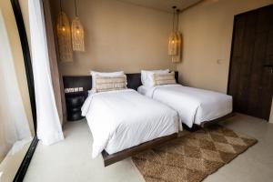 two beds in a room with white sheets and pillows at SISI Wellness Villas in Bingin Beach