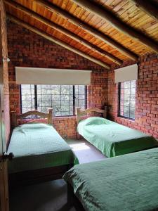 two beds in a room with a brick wall at La Toscana, Chalet Campestre in Guasca