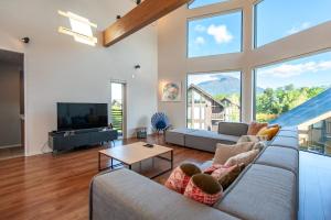 a living room with a couch and a tv and large windows at The Orchards Niseko in Kutchan