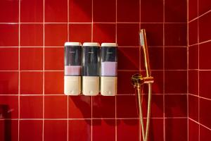 a group of three lipstick bottles on a red tiled wall at Casa Bamba in Veracruz +63 photos