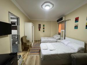 a room with two beds and a couch and a tv at Akhnaton pyramids inn in Cairo