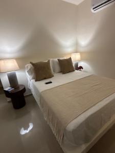 a bedroom with a large white bed with two lamps at Ocean Inn- Sector el Bluff in Bottom House