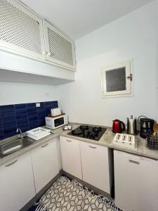 a kitchen with white cabinets and a stove top oven at Cosy 1BD Pool, Beach, Large Terrace in Hammam Sousse