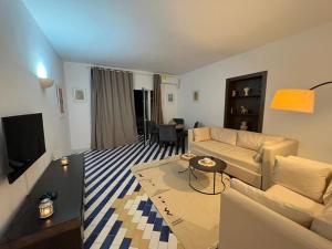 a living room with a couch and a tv at Cosy 1BD Pool, Beach, Large Terrace in Hammam Sousse +1 photo