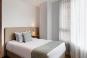 sypialnia z białym łóżkiem i oknem w obiekcie VOU Suites by Avia Suites w mieście Bogota
